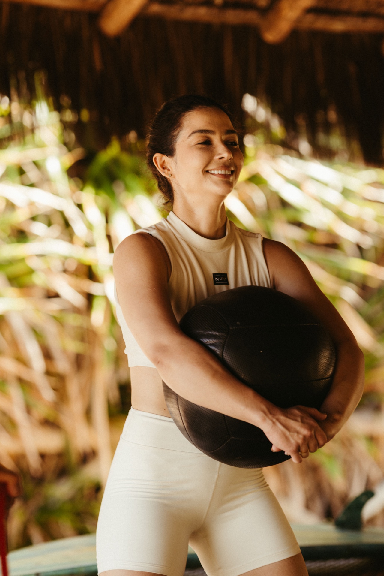 A smiling gym member holding a medicine ball