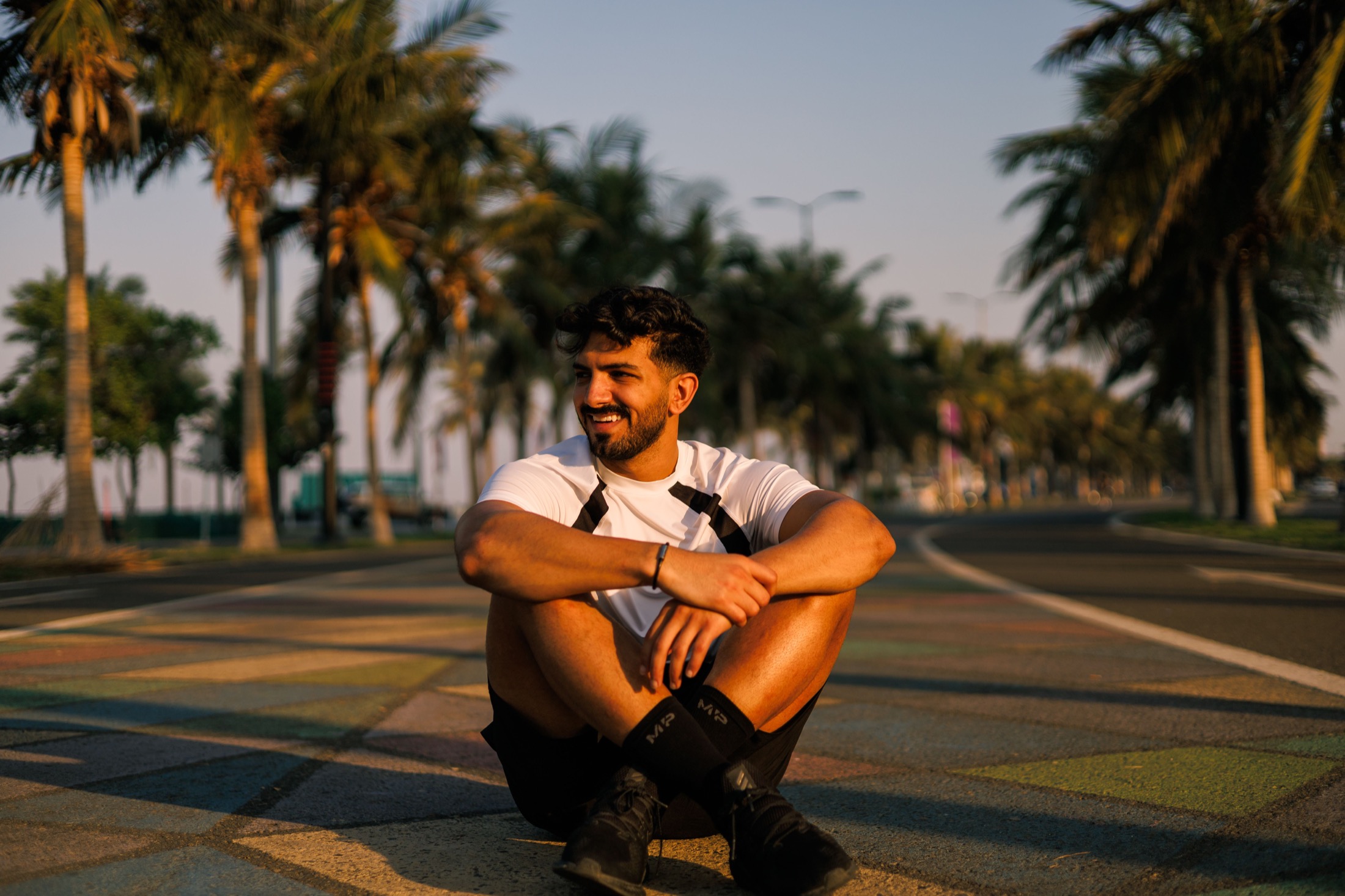 A gym owner sitting on a quiet palm-lined road